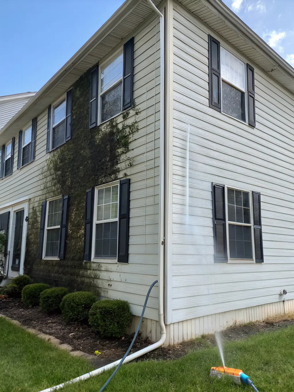A residential house in Houston, TX, with half of the siding visibly clean from power washing, showcasing the dramatic before-and-after effect.