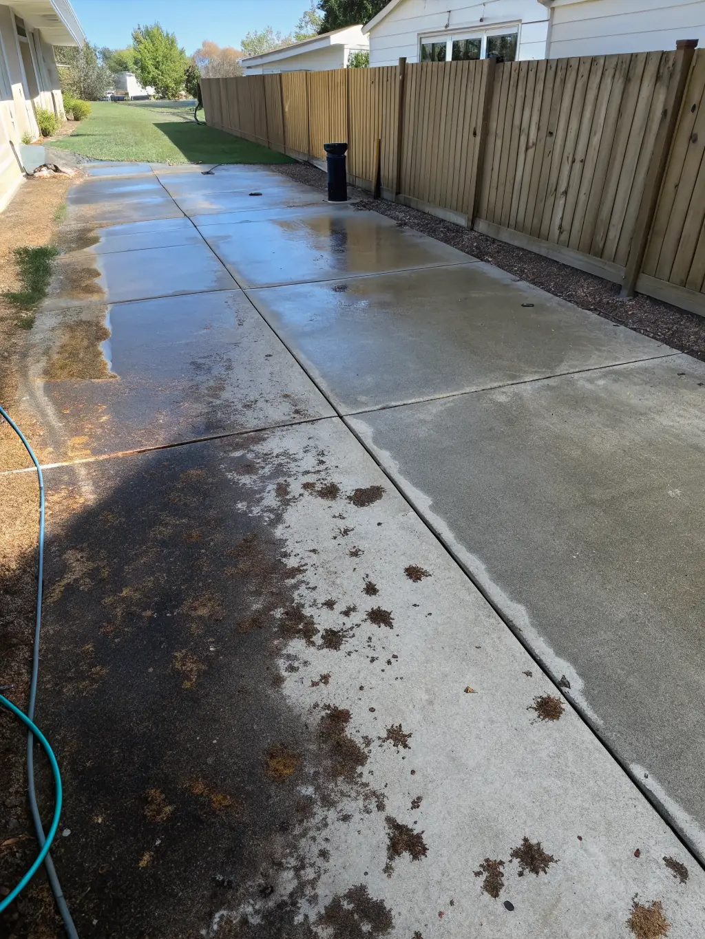 A before-and-after shot of a heavily stained driveway in Houston, TX, completely cleaned by Stuffy's power washing service.
